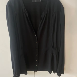 Svart blus - En jättefin svart blus från Åhléns. Blusen har guldknappar och är i storlek 40. Bra skick