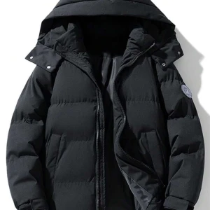 Svart dunjacka med huva - Snygg och varm svart dunjacka med huva och dragkedja. Perfekt för kalla vinterdagar. Jackan har en stilren design med långa ärmar och en diskret logga på ärmen.