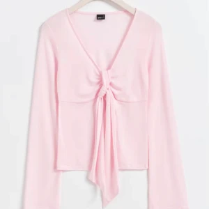 Rosa långärmad topp - Säljer en söt rosa långärmad topp med knytning framtill. Perfekt för en stilren och bekväm look. Toppen har en v-ringad design och är gjord i ett mjukt material. Aldrig använt typ❤️