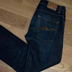 Nudie grim Tim  - Snygga mörkblå jeans från Nudie i storlek W31 L32. Har dessvärre ett hål i ena framfickan och en liten slitning i grenen. Priset går att diskuteras vid snabb affär, tveka inte på att höra av er!