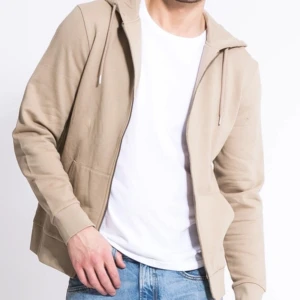 Beige hoodie med dragkedja - Snygg beige hoodie med dragkedja och huva. Perfekt för en avslappnad stil. Den har långa ärmar och en bekväm passform.