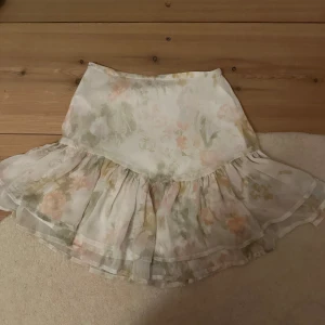 Blommig kjol med volang - Charmig blommig kjol i ljusa pastellfärger med volangdetaljer. Perfekt för en somrig look.