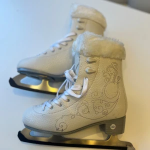 Prinsess konståkningsskridskor 39/40 - Vita konståkningsskridskor i storlek 39/ 39,5/ 40.  Mjukt gosigt varmt foder och exklusiv design för skridskoprinsessa.   Nyskick, endast använda en gång då jag behöver en större storlek.  Kan även passa storlek 38/ 38,5 om man föredrar att ha tjockare strumpor/raggsocka.   Märkta som storlek 39/40 (se bild) och 40 på etikett.   Innermått 25,5 cm  Går ej längre att köpa online/i butik då affären upphört.