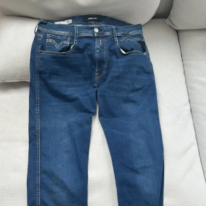 Blå jeans från Replay - Säljer ett par snygga blå jeans från Replay, modell Anbass. De har en slim fit passform och är tillverkade i Hyperflex-material för extra komfort. Klassisk femficksdesign med dragkedja och knapp. Perfekta för en stilren look. Storleken är 32/36. Priset går självklart att diskutera och det är bara att höra av sig vid frågor!