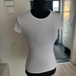 Vit kortärmad t-shirt - Snygg och enkel vit t-shirt med korta ärmar. Perfekt basplagg för alla tillfällen. Den har en rund halsringning och en figurnära passform.