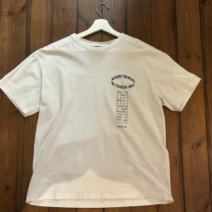 Vit graphic T-Shirt från H&M - Säljer en vit t-shirt från H&M med tryck både fram och bak. Texten 'Always Forward No Turning Back' ger en cool vibe. T-shirten är i bomull och har en relaxed fit, perfekt för en avslappnad stil.