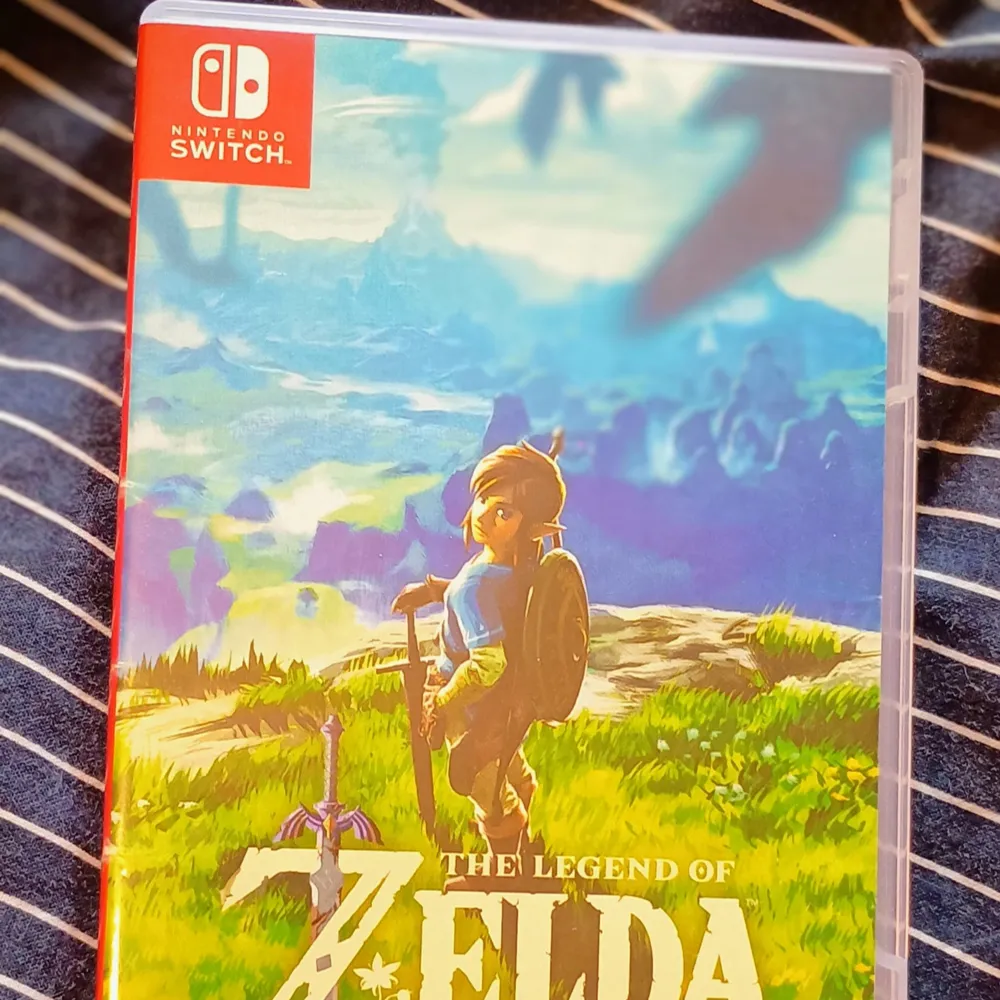 Säljer spelet The Legend of Zelda: Breath of the Wild för Nintendo Switch. Utforska en vidsträckt värld och överlev i vildmarken medan du kämpar för Hyrules framtid. Spelet kommer i originalförpackning med vackert illustrerat omslag.. Böcker.