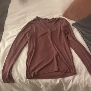 Ribbad långärmad tröja från lager 157 - Säljer en stilren ribbad tröja i en mjuk brun nyans från lager 157. Tröjan har en v-ringad hals och långa ärmar, perfekt för kyligare dagar. Passar bra till både jeans och kjol.