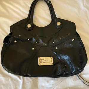 Svart handväska från Guss Los Angeles - Jättesöt guess väska!💕Lite sliten på handtagen men annars i bra skick!