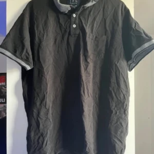 Svart kortärmad pikétröja J.K.F - Snygg svart pikétröja från Lyle & Scott med korta ärmar och knappar framtill. Perfekt för en avslappnad stil.