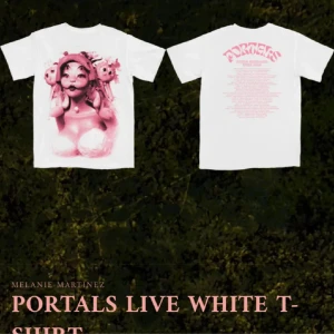 Vit Portals Live T-shirt - Vit t-shirt med tryck av en konstnärlig design i rosa på framsidan och text på baksidan. Kortärmad och perfekt för fans av Melanie Martinez.
