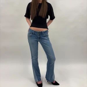 Blå lågmidjade bootcut jeans - LTB Jeans storlek 29/32 med en detalj vid bensluten. Modellen är 172🤗