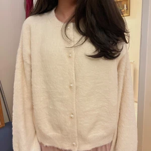 Vit kofta med pärlknappar - Säljer denna mysiga vita koftan med långa ärmar och dekorativa pärlknappar framtill. Den är inte använd många gånger. Skriv om du har frågor!
