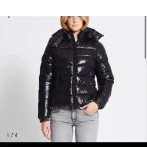 Lager 157 jacka - Snygg svart pufferjacka med glansig yta och dragkedja framtill. Jackan har en hög krage och långa ärmar, perfekt för kyligare dagar. En stilren och praktisk jacka för alla tillfällen.