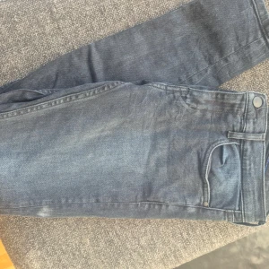 Blå super skinny jeans från Calvin Klein - Snygga blå super skinny jeans från Calvin Klein i premium italienskt tyg. De har en midwaist passform och klassiska femficksdetaljer. Perfekta för en stilren look.
