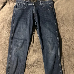 Mörkblå jeans från Replay - Snygga mörkblå jeans från Replay med klassisk femficksdesign och knappgylf. Perfekta för en avslappnad stil med en modern touch. Passar bra till både sneakers och kängor. Storlek 31:32