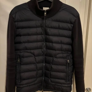 Moncler cardigan - Ett riktigt snygg marinblå moncler cardigan i storlek M. Självklart äkta😃Jackan har ett litet hål på höger armen (se bild 5) och hängaren har gått sönder (se bild 4) Men det är ingenting som syns vid användning. Eftersom jackan har små defekter tillkommer även det nedsatta priset. Hör gärna av er vid frågor och fler bilder! KVITTO FINNS