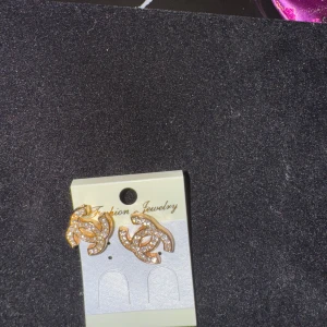 Guldörhängen med glittriga detaljer - Helt NYA! Snygga guldörhängen med glittriga stenar i ett elegant mönster. Perfekta för att ge en touch av glamour till din outfit. De är små och diskreta men ändå iögonfallande.