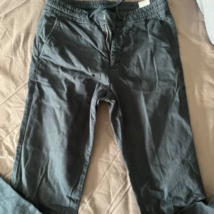 Mörkblå byxor med knytning - Snygga mörkvlå byxor med elastisk midja och dragsko. De har en dragkedja samt snörning framtill och är perfekta för en avslappnad stil. Har även fickor på sidan