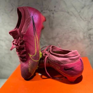 Snygga och snabba fotbollsskor från Nike - Säljer ett par Nike Zoom Vapor 15 Pro FG. Riktigt fräscha och snygga, cool färg som sticker ut på planen. Box ingår. Nypris: 1700 kr