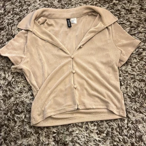 Unik topp från h&m - Beige unik topp från h&m med knappar och lite genomskinligt material