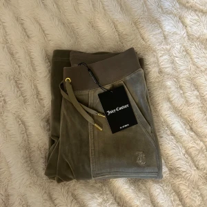 Gröna mjukisbyxor från Juicy Couture - Del ray pants från Juicy Couture i storlek XS i färgen vetiver. Aldrig använda, helt nya med lapp, Dock defekt se sista bilden, går däremot enkelt att laga hos skräddare om man stör sig på det, men därav lägre pris. 