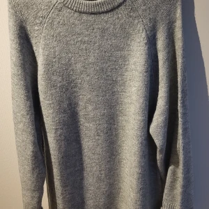 Grå stickad klänning - Mysig grå stickad klänning perfekt för kyliga dagar. Tröjan har en klassisk design med långa ärmar och en bekväm passform. Perfekt för att hålla sig varm och stilren under höst och vinter. Aldrig använd. 