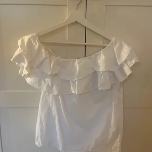 Vit offshoulder topp från NA-KD - Säljer en söt vit offshoulder topp från NA-KD med volangdetaljer. Perfekt för en sommar topp🩷🩷
