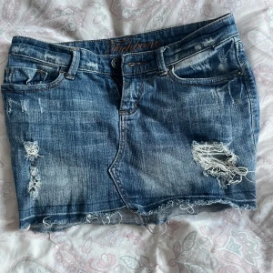 Blå jeanskjol från Fishbone - Snygg blå vintage jeanskjol från Fishbone med slitna detaljer!