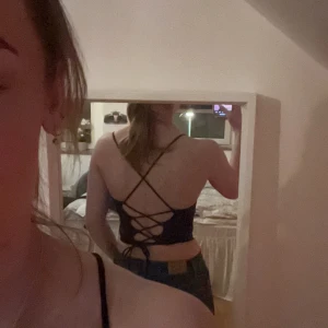 Svart linne med snörning - Snyggt svart linne med smala band och snörning i ryggen. Perfekt för en stilren och trendig look. Passar bra till både jeans och kjol. Pris kan diskuteras 