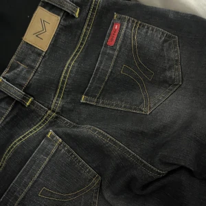 Svarta jeans med gula sömmar - Snygga svarta jeans med kontrasterande gula sömmar och klassisk femficksdesign. Skriv vid frågor och kolla järna in annat jag säljer💗Skille säga midja xs-s och längd ungefär 165-170