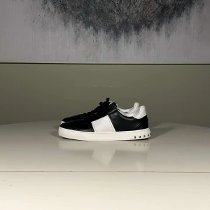 Valentino Flycrews svarta  - STORLEK 40 PASSAR 41 42Valentino flycrews i nyskick. Snygga svartvita sneakers med nitar på sulan. Skorna har en stilren design med svart ovandel och vita detaljer. Perfekta för en trendig look.