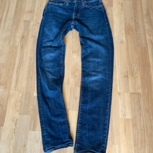 Blå och svarta Levis 511 - Två par jeansbyxor, ett par i klassisk blå denim och ett par i svart. Båda har en straight passform med femficksdesign och knappgylf. Perfekta för en avslappnad stil. W28 L32 på båda. 200 kr för båda