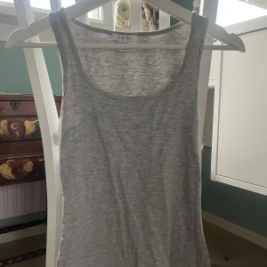 Grå linnetopp från New yorker  - Säljer en enkel och stilren grå linnetopp från Amisu (New yorker). Perfekt för varma dagar eller som lager under en tröja. Toppen har en klassisk rund halsringning och ärmlös design.
