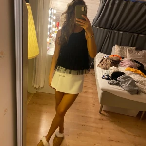 Svart ärmlös topp med paljetter - Snygg svart ärmlös topp med flera lager av volanger och en glittrig paljettkrage. Perfekt för en kväll ute eller en speciell tillställning. Toppen har en luftig passform och ger en elegant look.