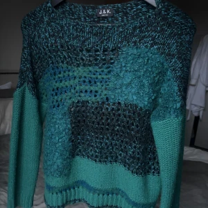 Grön stickad tröja från J&K - Säljer en unik grön stickad tröja från J&K med ett coolt mönster i olika gröna nyanser. Tröjan har långa ärmar och en rund halsringning. Perfekt för att hålla sig varm och stilren under kyliga dagar.