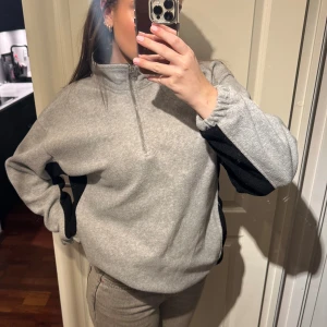 Grå fleece med dragkedja - Säljer en mysig grå fleece med dragkedja och svarta detaljer på ärmarna. Perfekt för kyliga dagar. Den har en avslappnad passform och är superbekväm att bära. Köpt secondhand, storlek M🪩