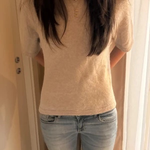 Beige trekvartsärmad tröja - Säljer en stilren beige tröja med korta ärmar. Perfekt för en avslappnad look. Tröjan har en mjuk och bekväm passform.