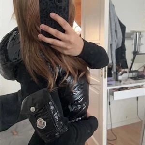 Svart glansig pufferjacka med huva - Säljer en svart glansig moncler cardigan. Storlek xs/s/m beroende på hur man vill den ska sitta. Jag själv bär storlek s och den sitter perfekt på mig. Ganska varm och passar perfekt till vår/höst. Passar både tjejer och killar då jackan är unisex. Har endast använt jackan ute en gång. 