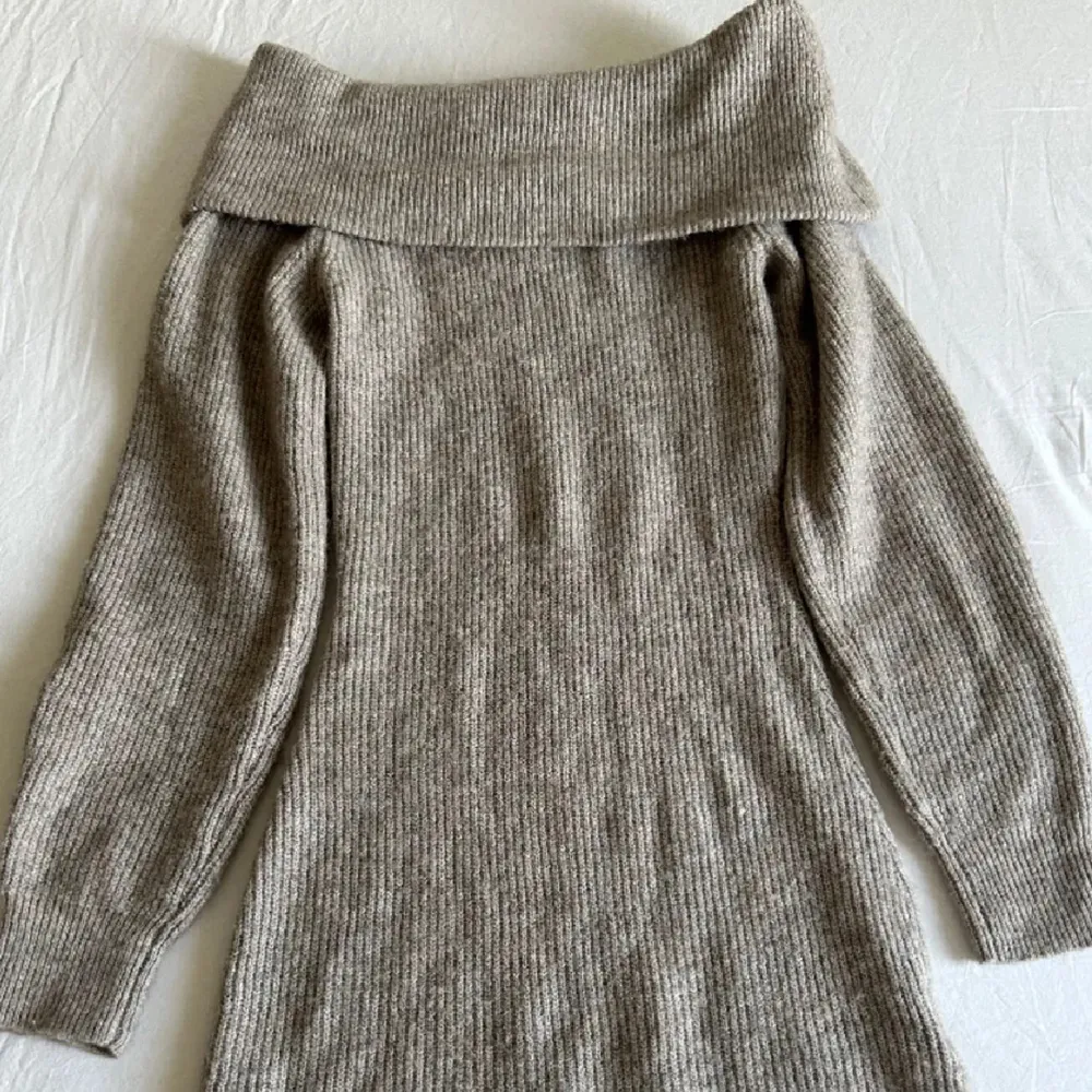 Säljer en superfin beige stickad klänning med offshoulder-design. Den har en tight passform och långa ärmar, perfekt för kyligare dagar. Klänningen är ribbad och ger en stilren look. Perfekt för att hålla sig varm och snygg samtidigt användes bara en gång så den är nästan ny och helt felfri❤️. Mekot.