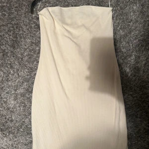 Beige ribbad klänning från mango - Säljer en stilren beige ribbad klänning från mango. Den är axelbandslös och har en tight passform som framhäver figuren, knappast använd och har inga tecken på användning💕