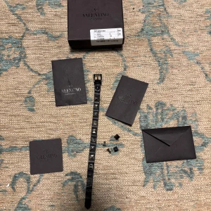 valentino armband - Säljer ett snyggt svart armband från Valentino med silverfärgade nitar. Armbandet är i skinn och har en justerbar spänne för perfekt passform. Kommer med originalförpackning och certifikat. Nypris på denna är från 2500-2900 mitt pris 850