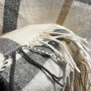 Rutig halsduk med fransar - Säljer en superfin rutig halsduk med fransar i ändarna. Den har en stilren design med rutor i grått, beige och vitt. Perfekt för att hålla sig varm under kyliga dagar. Passar både till vardags och lite finare tillfällen. 🧣✨från Åhléns 
