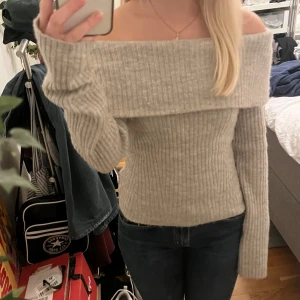 Beige offshoulder tröja från H&M - Säljer en superfin beige stickad offshoulder tröja från H&M. Tröjan har långa ärmar och en bekväm passform som sitter snyggt på axlarna. Lite lite nopprig men inget som syns!
