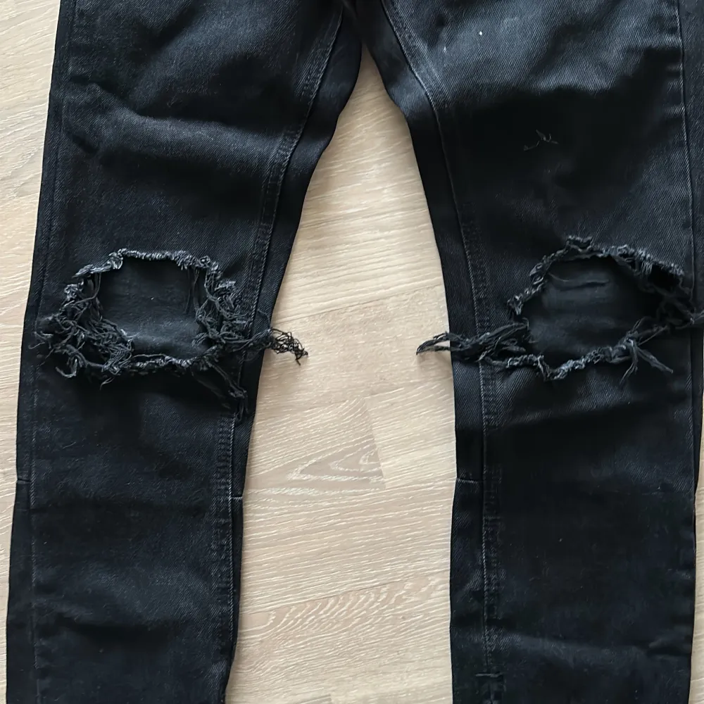 Säljer ett par skinny svarta jeans från mnml i bra skick. De har coola slitningar på knäna och en dragkedja vid bensluten. Perfekta för en avslappnad och trendig look. Köpta i Usa. Strlk 28. Jeans & Byxor.