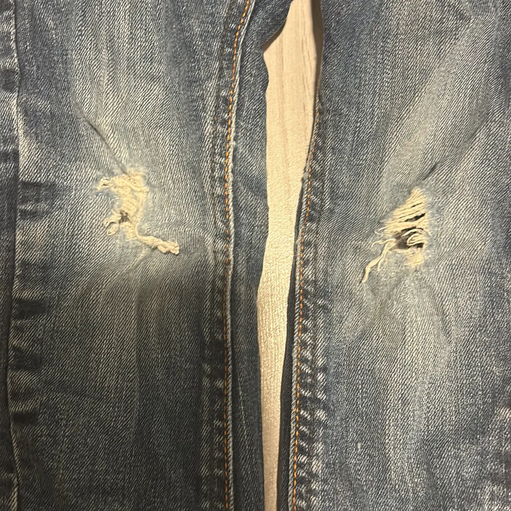 Säljer ett par coola blå jeans för barn från H&M i storlek 98. De har en snygg sliten look med hål på knäna och är i tapered stil. Perfekta för vardagsbruk och ger en trendig touch till vilken outfit som helst. De är i bra skick och redo för nya äventyr!. Jeans & Byxor.