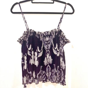 Topp - Säljer en superfin ärmlös topp med smala axelband och ett snyggt mönster i mörkblått och vitt. Aldrig använd 