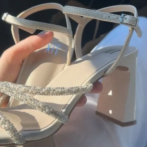 Beige klackar med pärl och glitterdetaljer - Säljer nu mina klackar jag använt på min bal,  är superfint skick förutom märken från foten i ”sulan” efter användning, Men inget som syns när man har de på! Bilderna i annonsen är från när de var helt nya. Strl 38, säljes för 150 kr