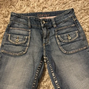 Blå capri jeans från Esprit - Säljer ett par snygga blå caprijeans från Esprit i bra skick. De har en klassisk femficksdesign med knappar och coola sömmar på bakfickorna. Tror att de är i en stl 36