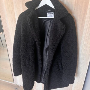 Svart teddyjacka - Mysig svart teddyjacka i bra skick endast använd ett fåtal gånger. Perfekt för kalla höst- och vinterdagar. Jackan har långa ärmar och en skön krage. Den är fodrad för extra värme och komfort. Passar både till vardags och lite finare tillfällen💕